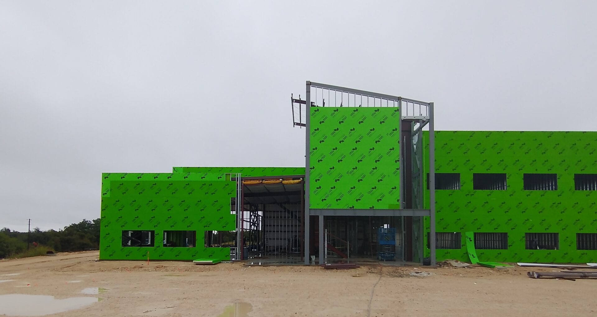 a large building under construction, with a green exterior and a metal frame