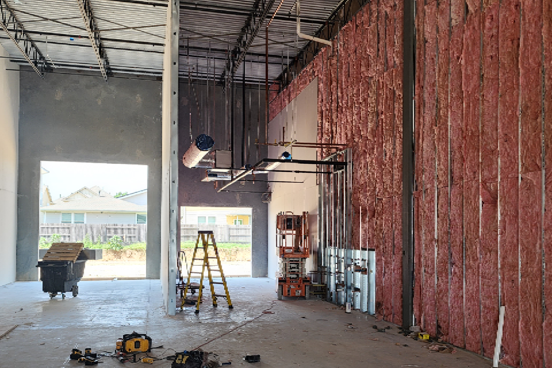 The building is being framed out with insulation, and there are various tools and equipment scattered around the area